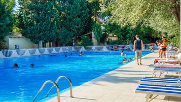 Relax by the pool surrounded by lush greenery and comfortable lounge chairs.