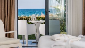 A hotel room with a balcony, a dining table with chairs, and a view of the ocean.