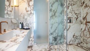 A modern bathroom with a marble vanity, a glass shower enclosure, and a marble-tiled shower area.