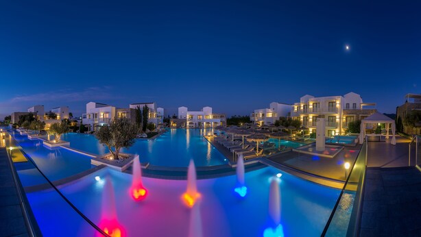 A resort with multiple swimming pools, some with water features, and a night sky.