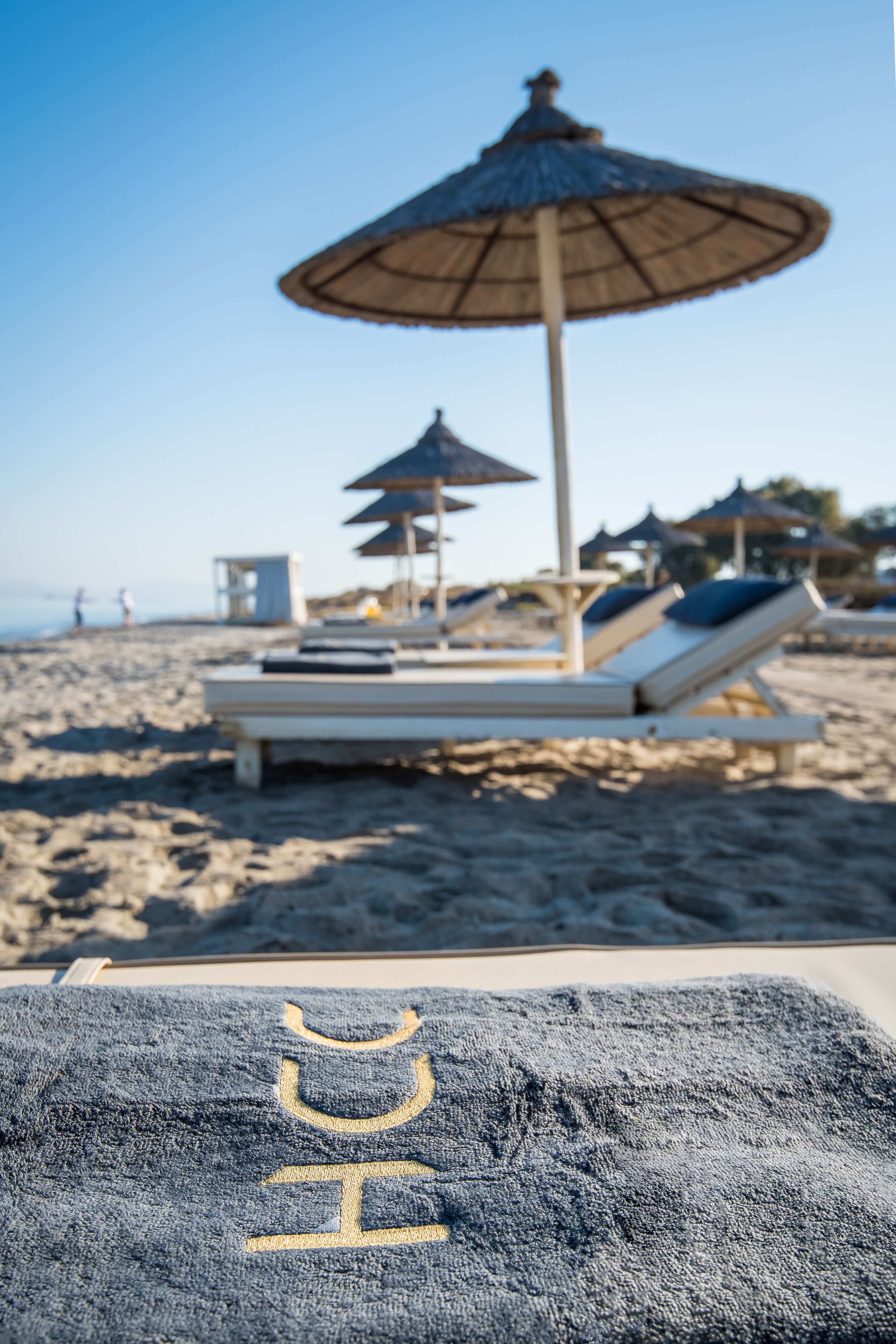 Una playa con sillas y sombrillas reclinables.