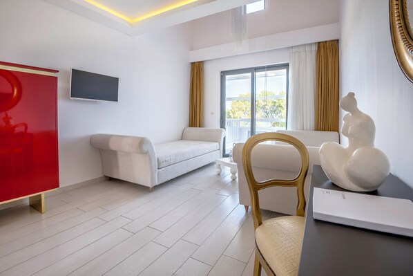 Una sala de estar moderna con un sofá blanco, un mueble de almacenamiento rojo, un televisor montado en la pared y un ventanal con cortinas.