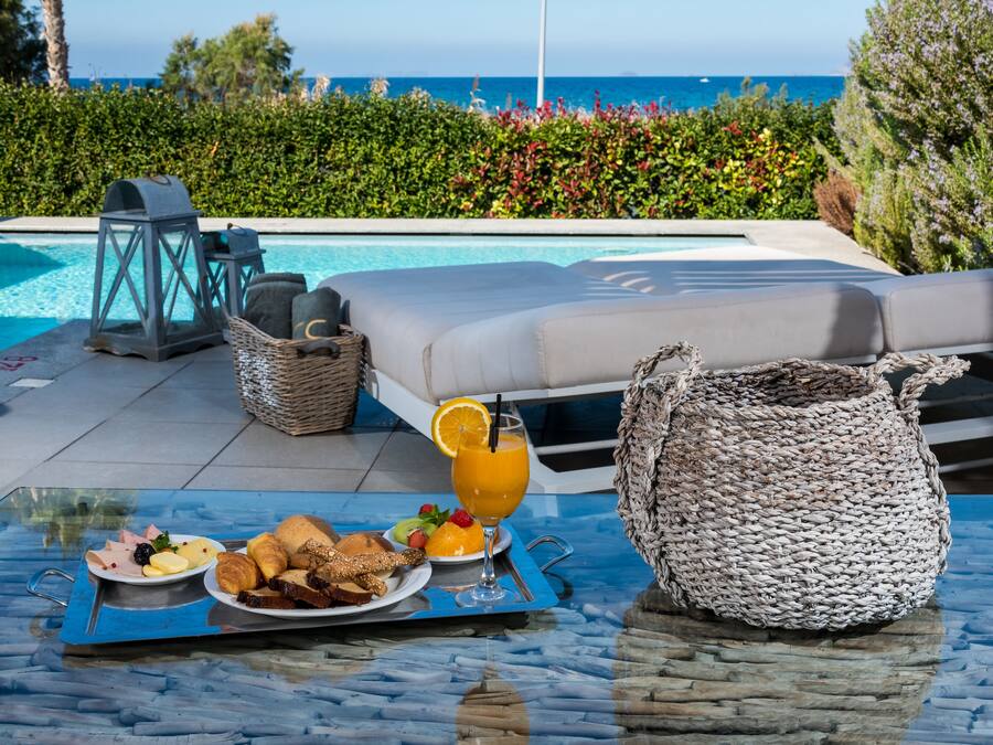 Colazione a bordo piscina, con un vassoio di cibo, una bevanda e un cesto di vimini.