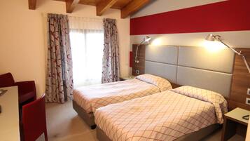 A hotel room with two beds, a desk, a chair, and a nightstand.