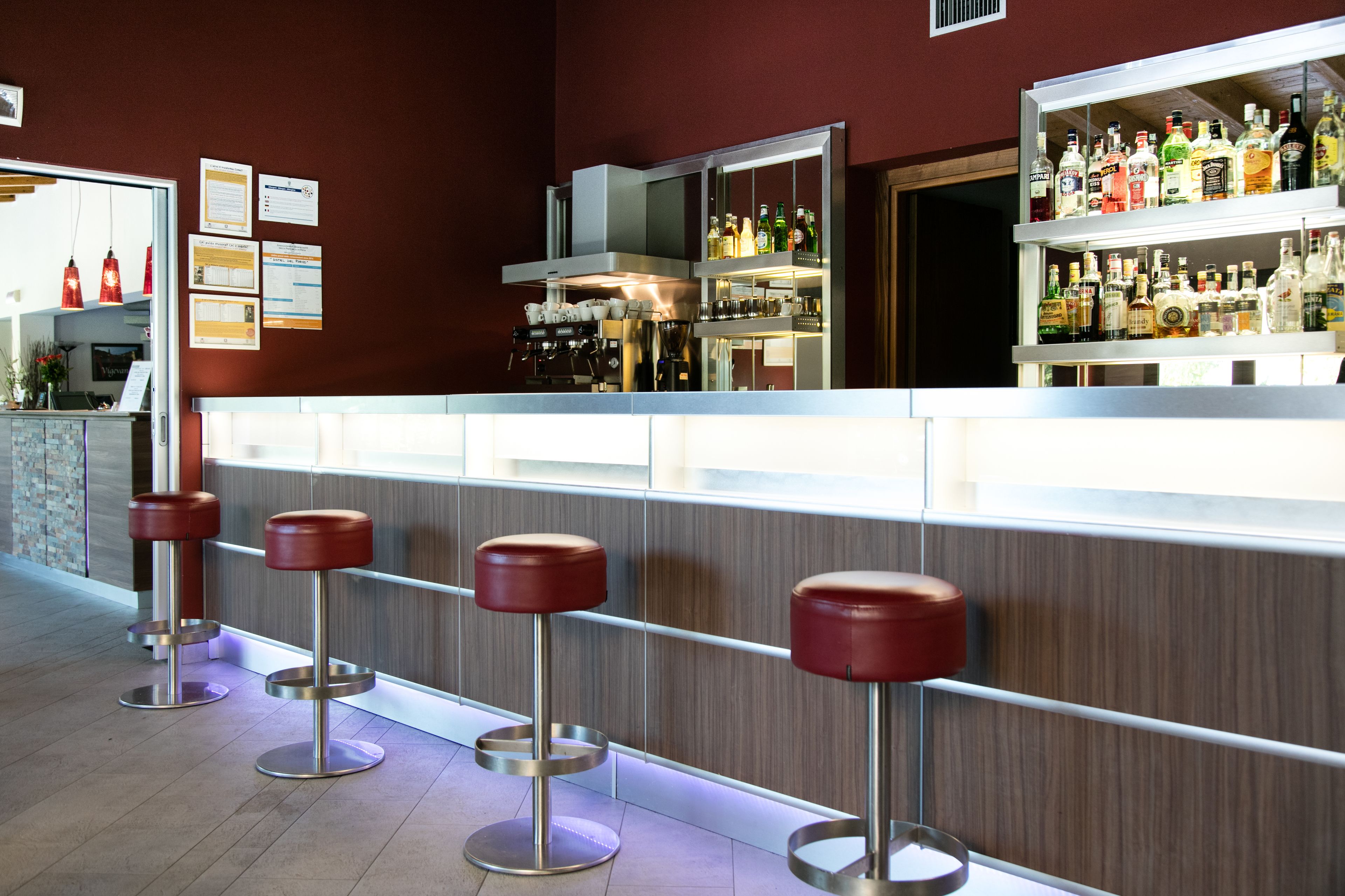 A bar area with stools, a counter, and shelves of bottles.
