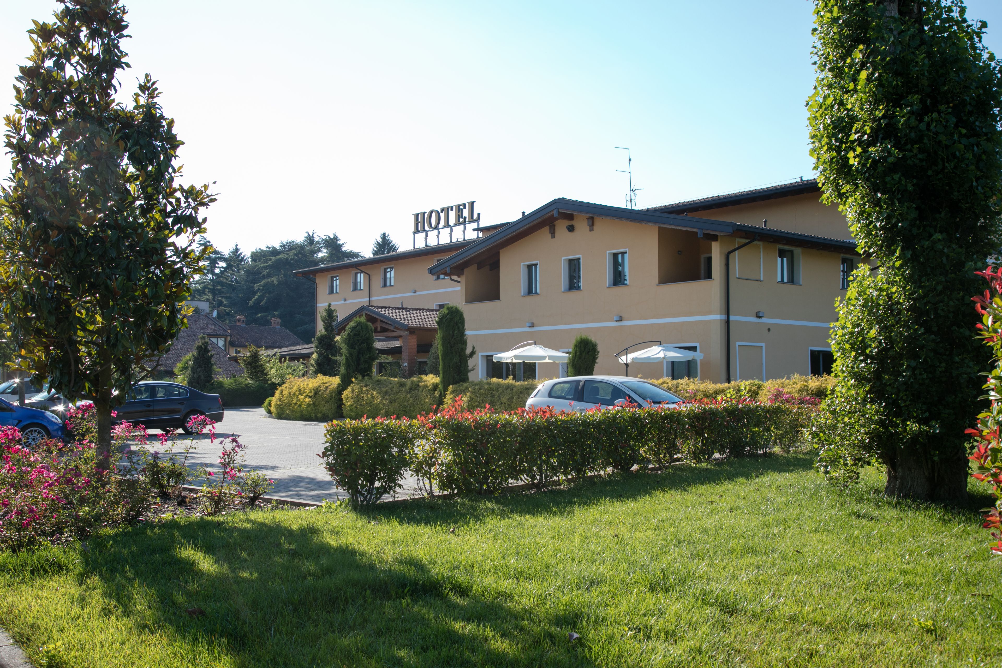 A hotel with a sign, a parking area, and well-maintained gardens.
