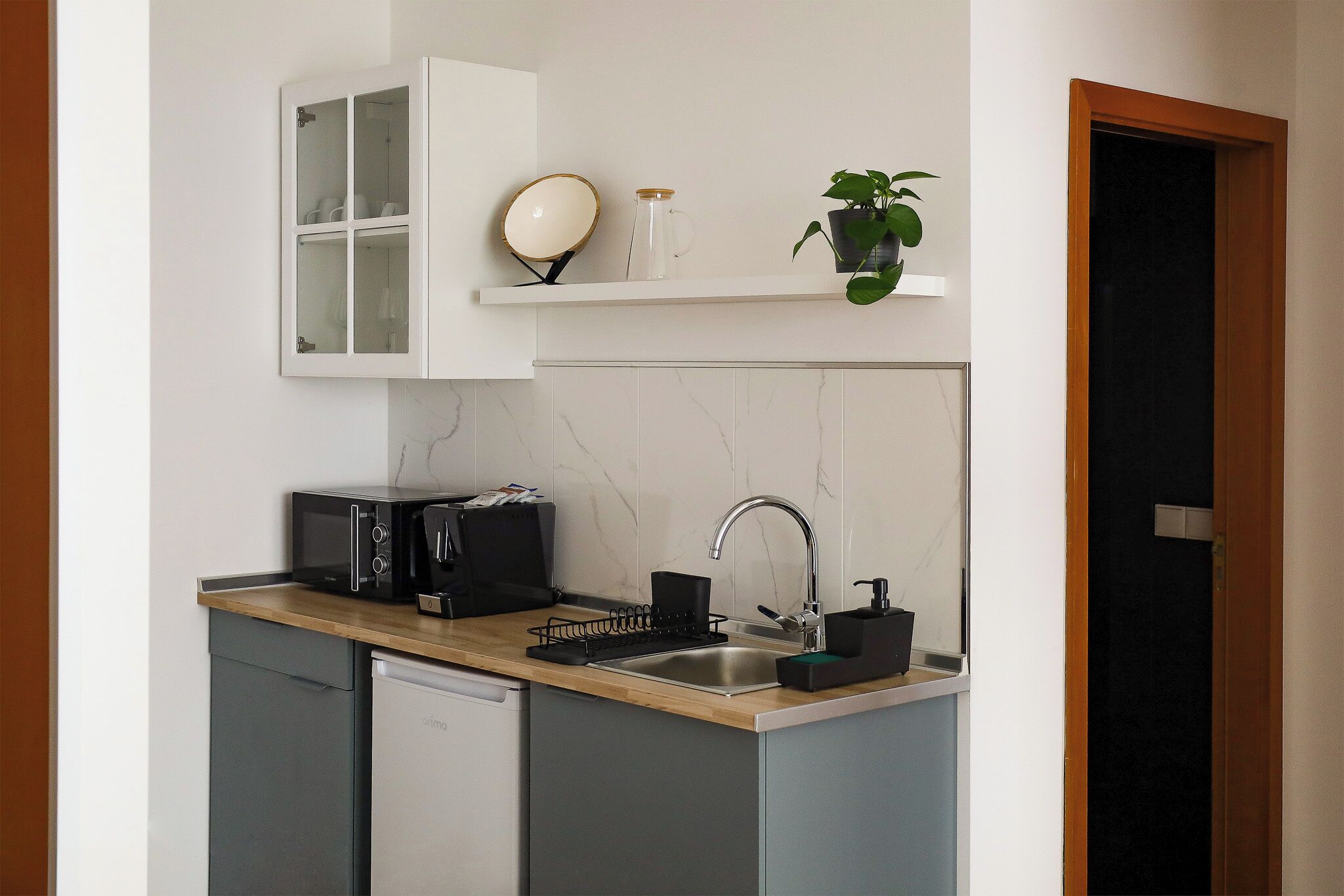 A compact kitchen with a microwave, sink, and cabinets.
