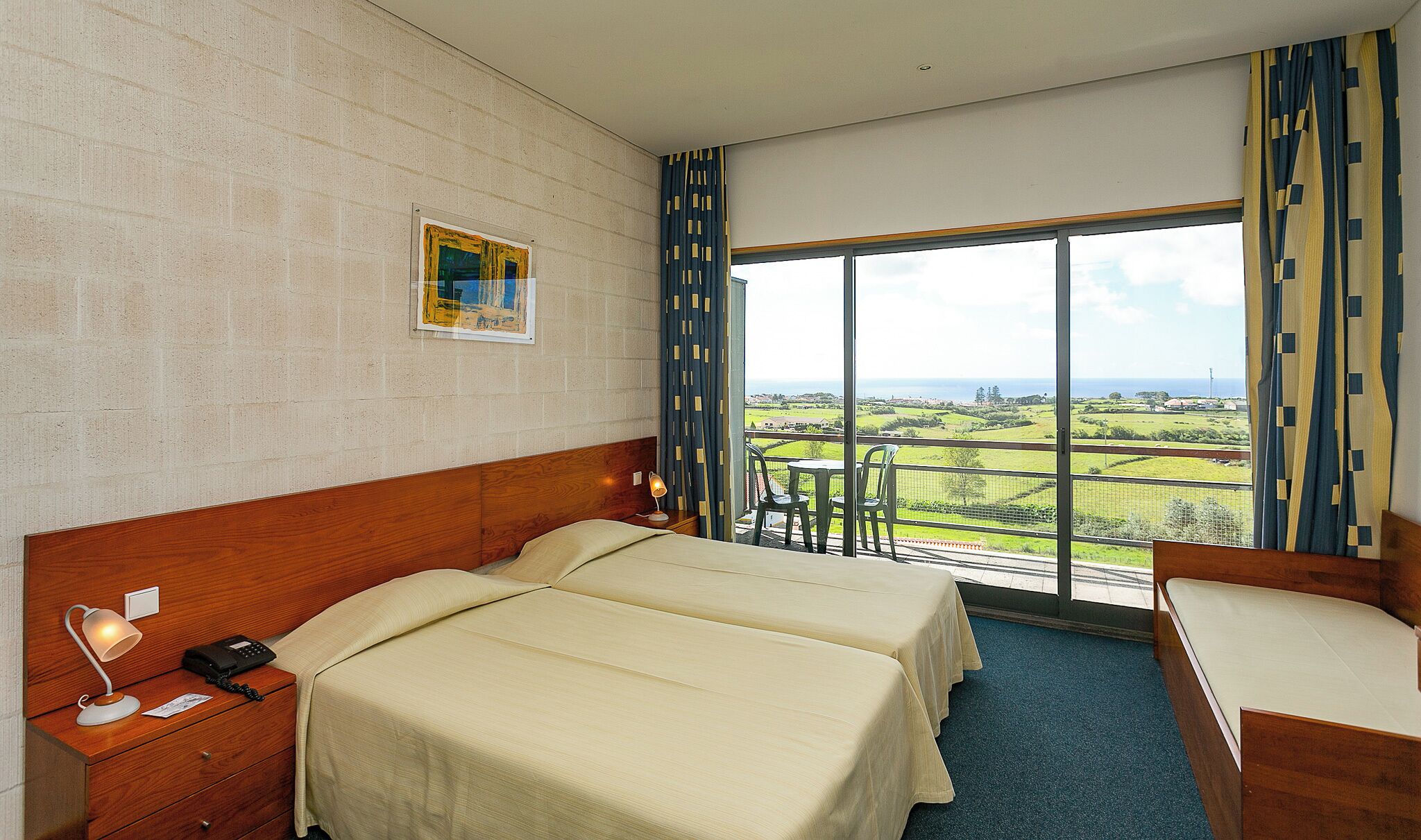 Une chambre d’hôtel avec deux lits, un bureau avec un téléphone, une chaise et une table.