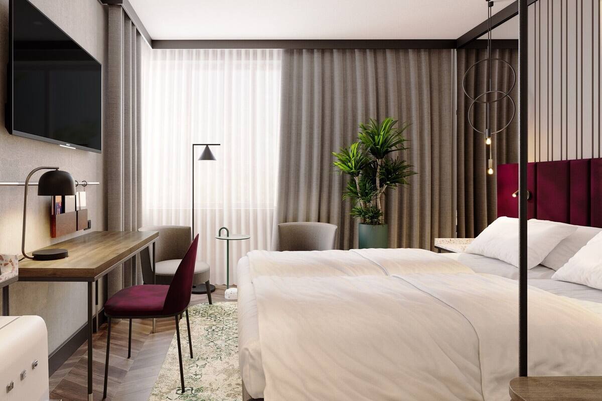 Habitación de hotel moderna con cama, escritorio, silla, televisión y una planta en maceta.