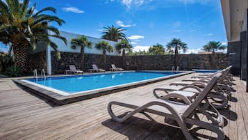 Piscina com espreguiçadeiras e palmeiras.
