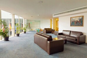 A spacious lobby with leather sofas, a coffee table, and potted plants. - Antillia Hotel (Ponta Delgada)
