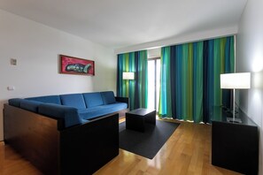 A modern living room with a blue sofa, a small table, and a lamp. - Antillia Hotel (Ponta Delgada)