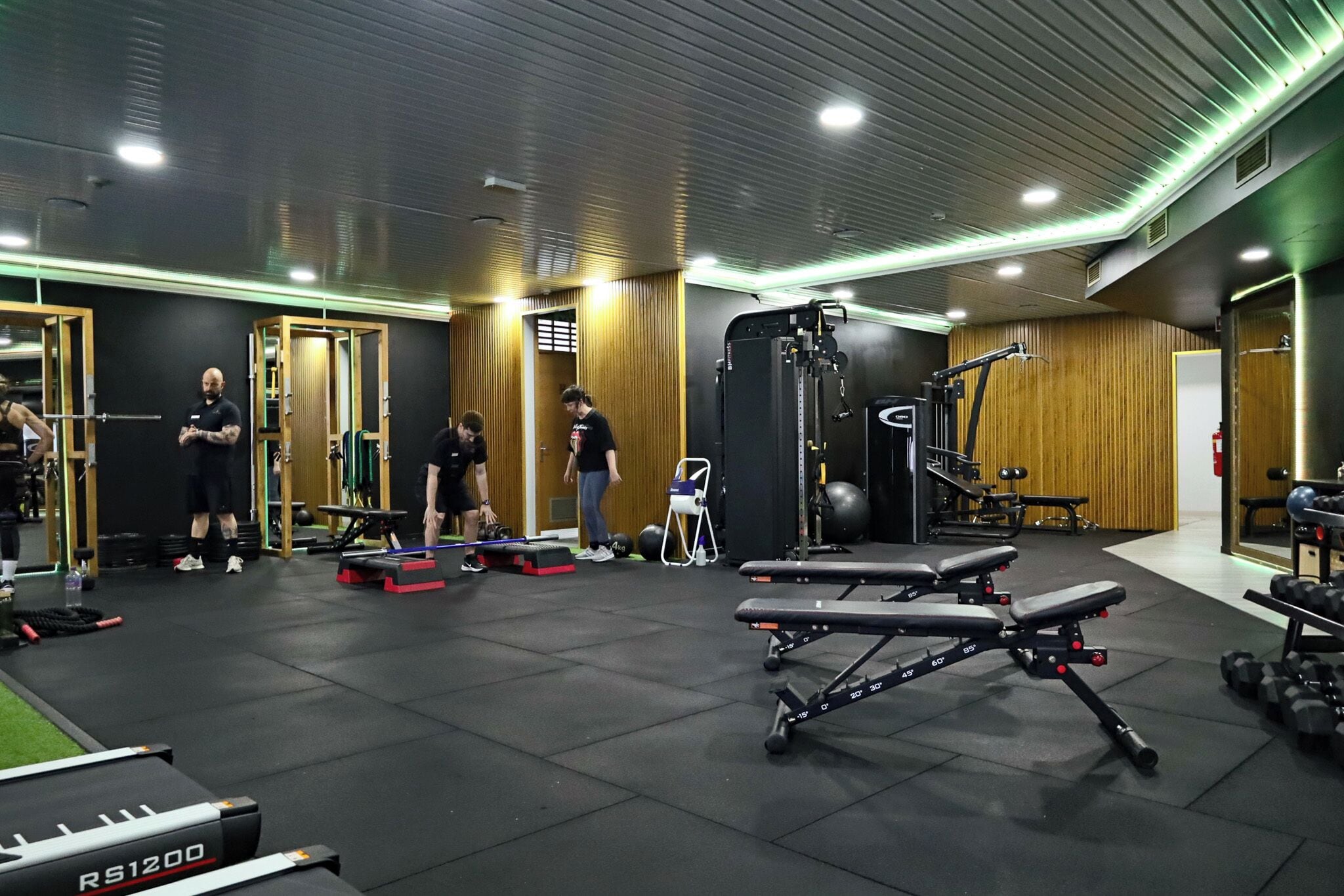Une salle de sport équipée de divers appareils d’exercice, notamment des bancs et des poids.