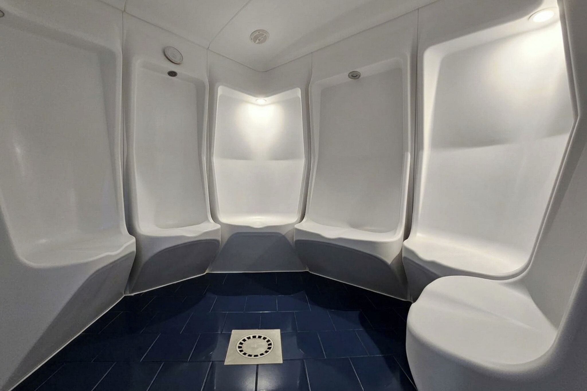 A restroom with three white urinals and a blue tiled floor.
