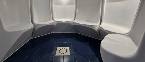 A restroom with three white urinals and a blue tiled floor.