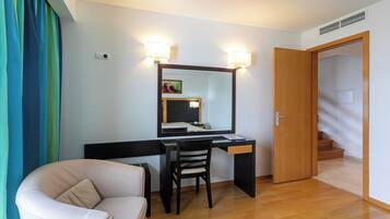 Habitación de hotel con escritorio, silla y cama. Se observa una puerta que da a una escalera.