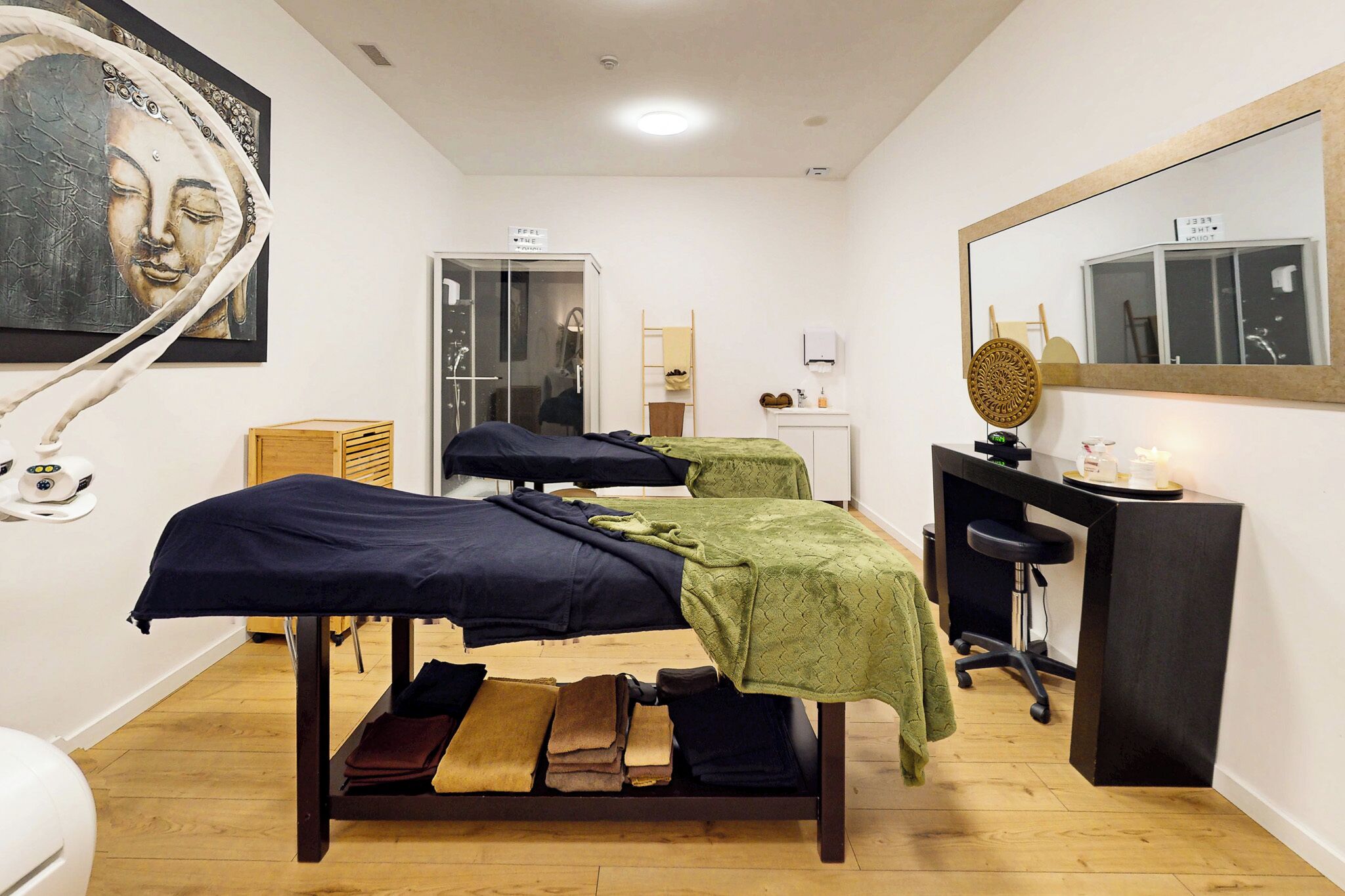 Una habitación con una camilla de masaje, un mueble de madera, un espejo y una ventana.