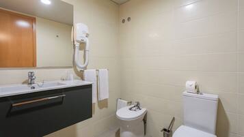 A bathroom with a sink, toilet, and bidet.