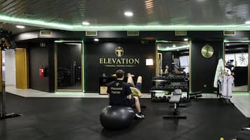 Een sportschool met een zwart en goud kleurenschema, met een klok aan de muur, gewichten en een zittende trainer.