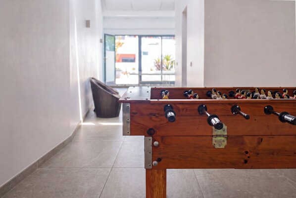 A foosball table in a hallway with a clear view of the outside through a glass door. - Antillia Hotel (Ponta Delgada)