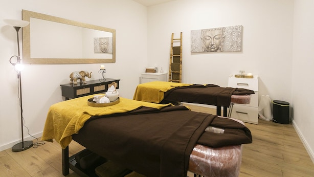 A room with two massage tables, a standing lamp, and artwork on the walls. - Antillia Hotel (Ponta Delgada)