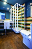 A modern bathroom with a shower enclosure, a toilet, and a sink with a mirror.