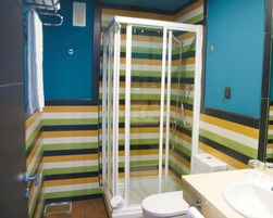 A bathroom with a striped floor, a glass shower enclosure, a white toilet, and a sink with a mirror.