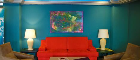 A room with a red sofa, two armchairs, a coffee table, and two lamps.
