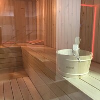 A sauna room with wooden benches and a white Harvia sauna tub.