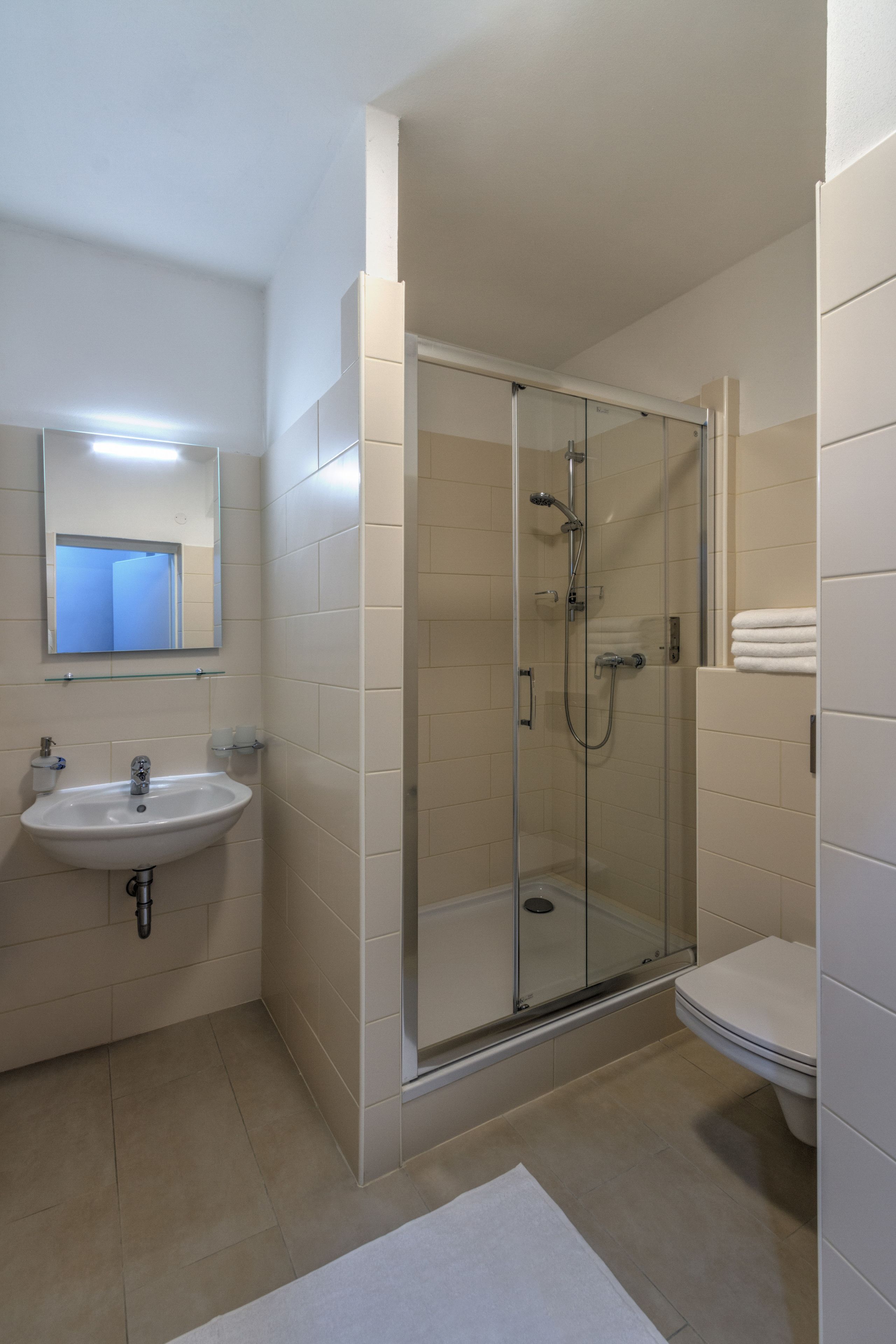 A modern bathroom with a glass-enclosed shower, a sink, and a toilet.