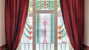 A window with stained glass and red curtains.