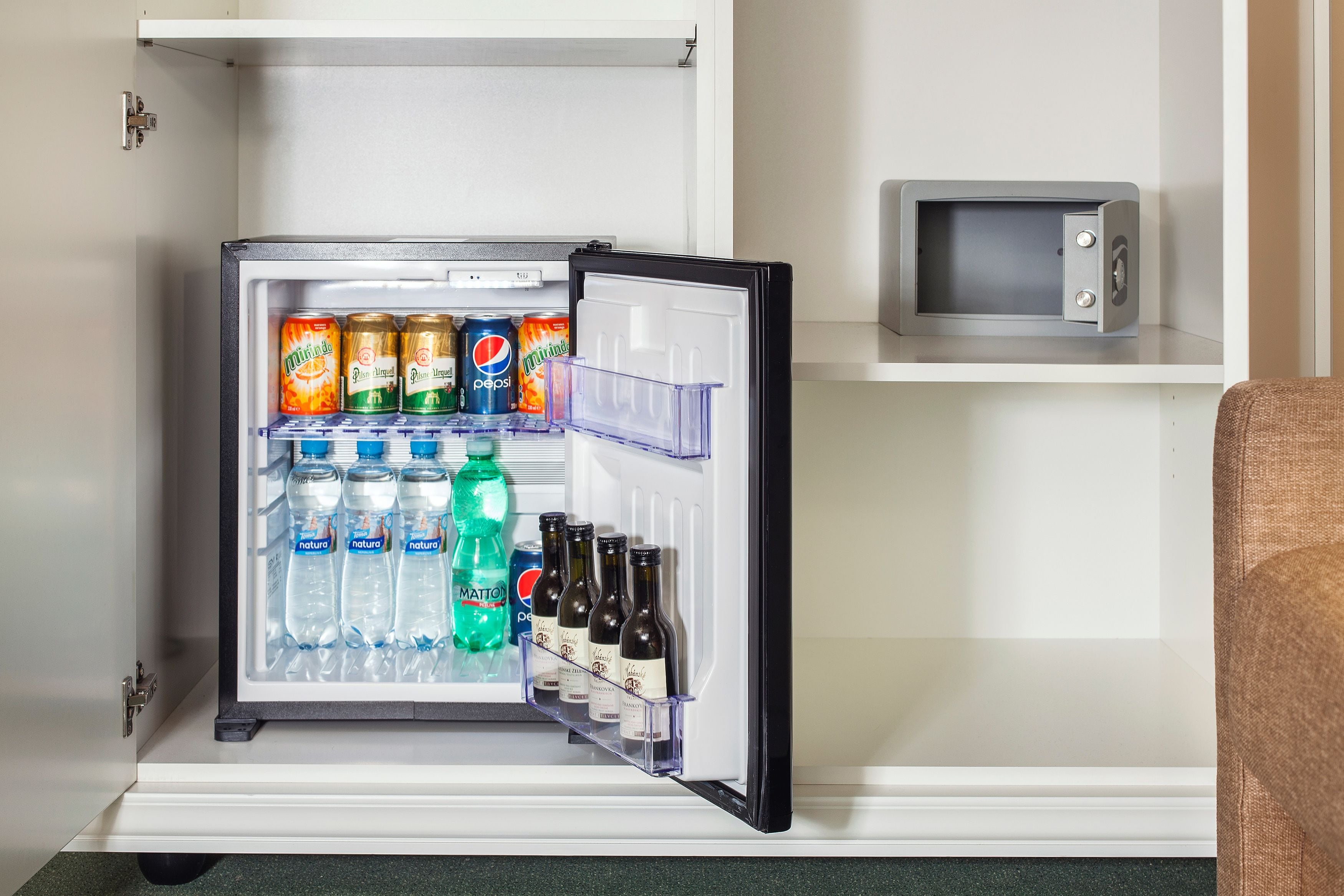 Un mini refrigerador con bebidas y un microondas encima.