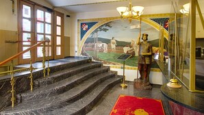 A grand staircase with marble steps and brass railings, leading to a room with a mural and a statue. - Hotel Taurus (Prague)
