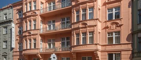 A pink building with multiple balconies and a sign reading "Hotel Taurus."