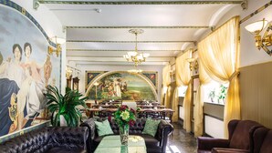 A luxurious room with a green table, leather sofas, and a mural on the wall.