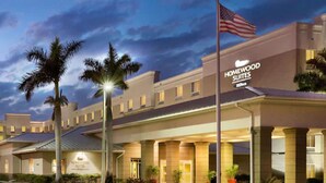 Un hotel con fachada moderna, un asta con la bandera estadounidense y una entrada bien iluminada.