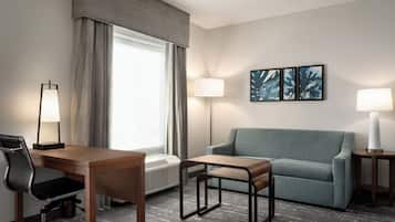Une chambre d’hôtel équipée d’un bureau, d’une chaise, d’un canapé et de deux lampes.