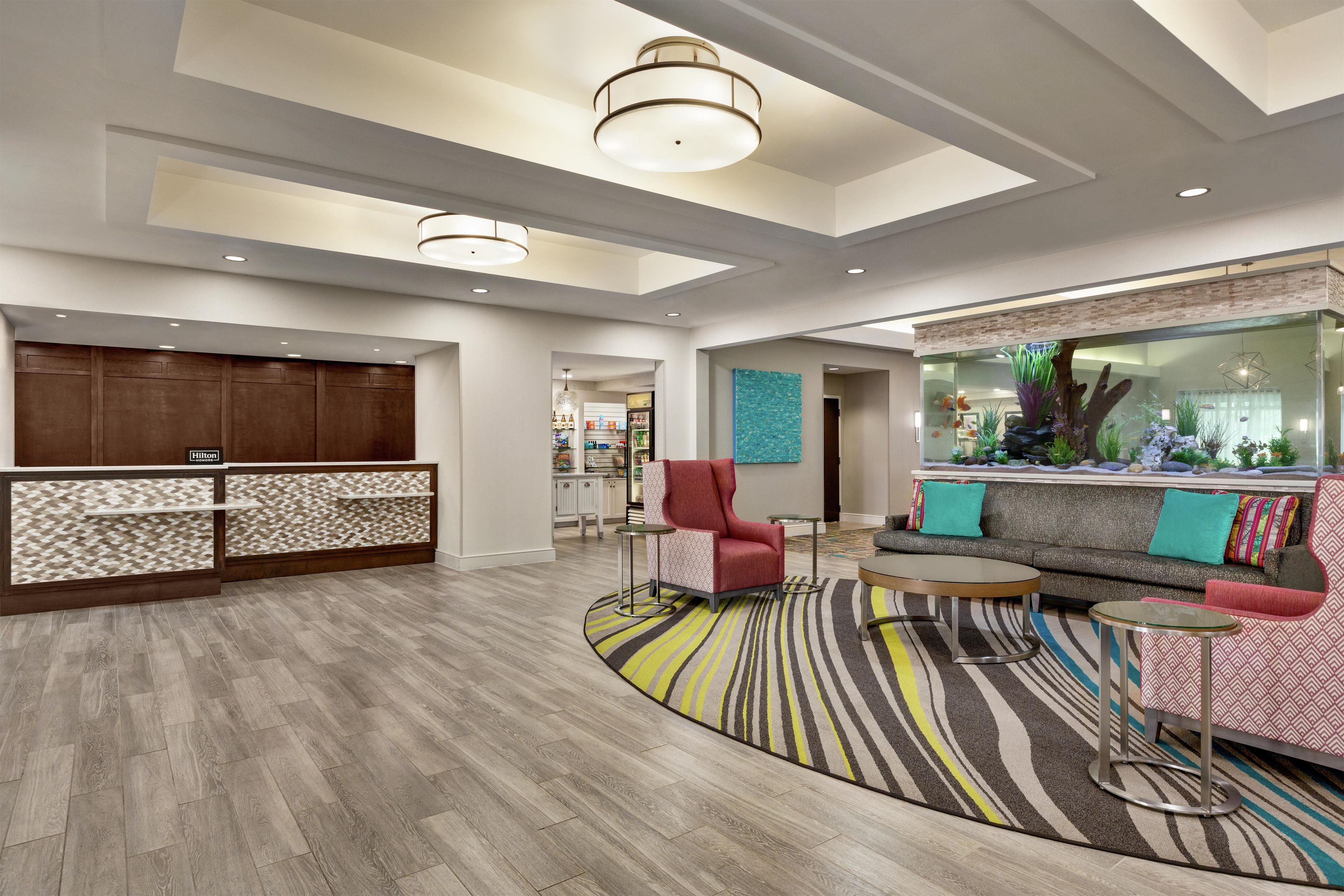 A hotel lobby with a reception desk, seating area, and a decorative aquarium.