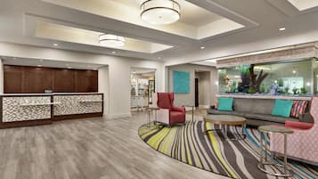 Un hall de hotel con mostrador de recepción, zona de estar y un acuario decorativo.