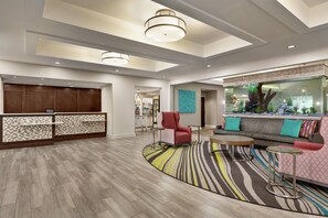 Un hall de hotel con mostrador de recepción, zona de estar y un acuario decorativo.