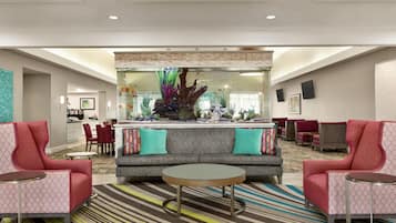 A lobby with a sofa, two armchairs, a coffee table, a fish tank, and a dining area.