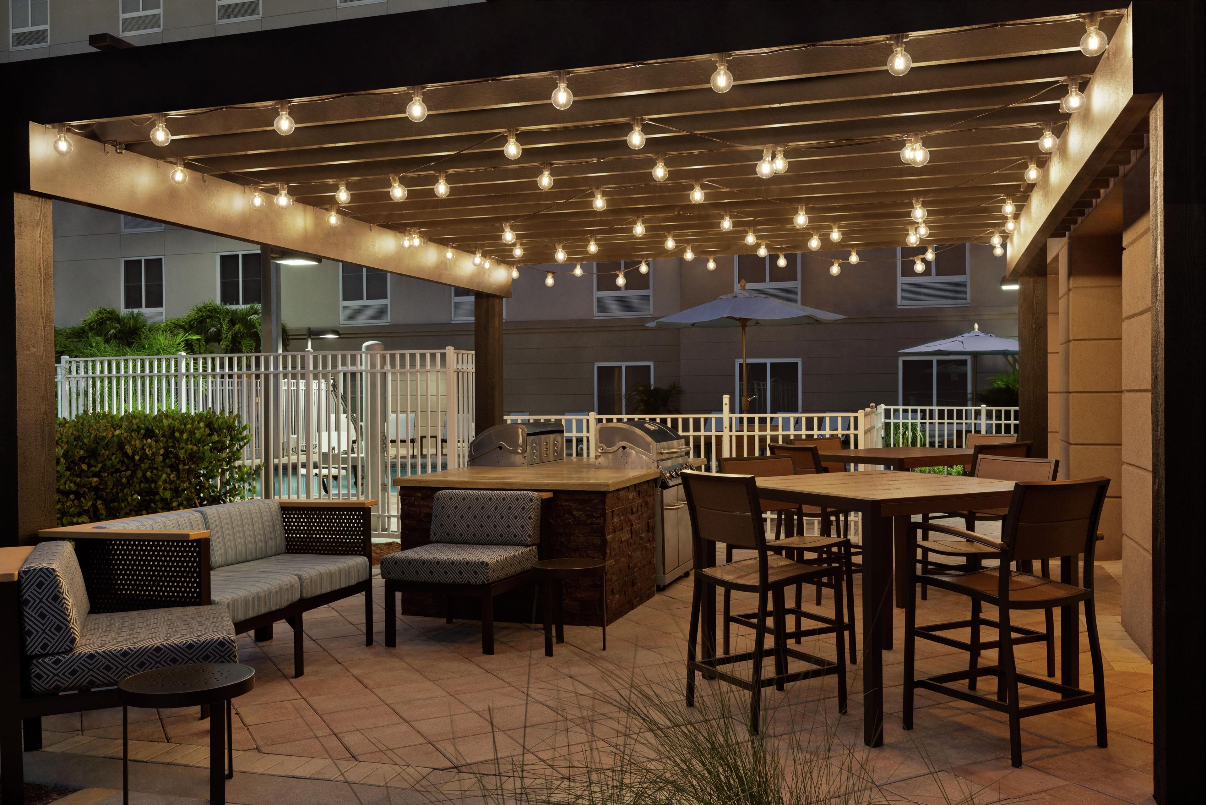 Eine Terrasse im Freien mit Grillplatz, Sitzgelegenheiten und Lichterketten.