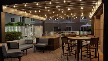 Eine Terrasse im Freien mit Grillplatz, Sitzgelegenheiten und Lichterketten.