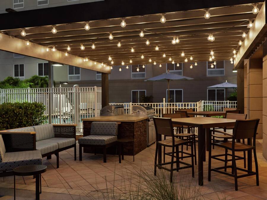 Un patio exterior con zona de barbacoa, asientos e iluminación con guirnaldas.