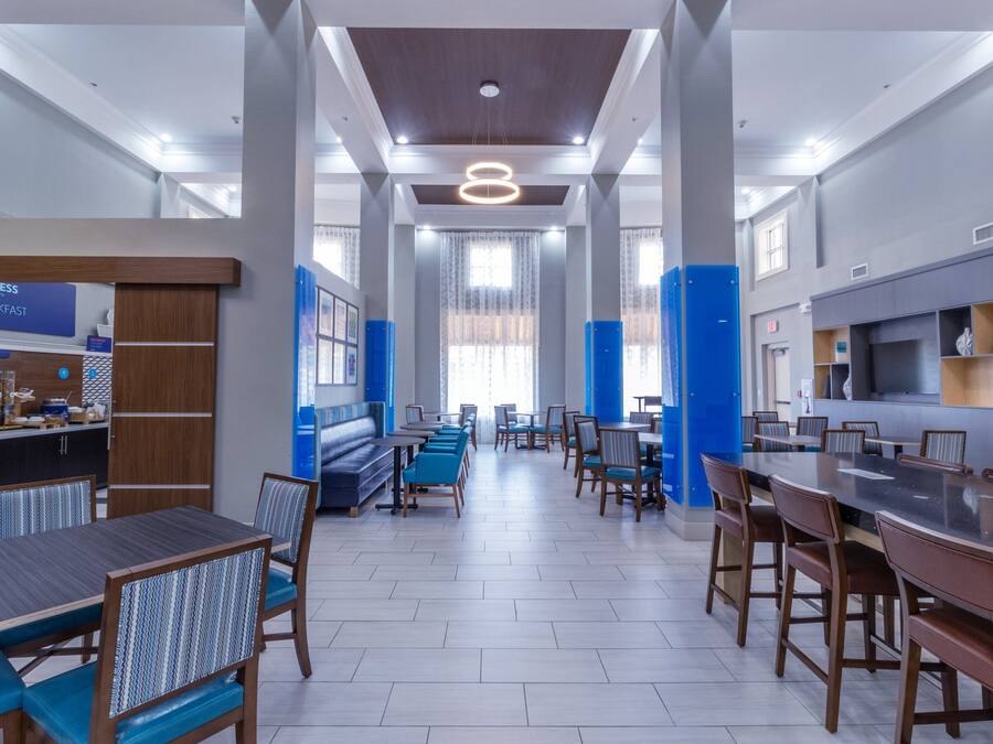 Um saguão moderno de hotel com área de estar central, cozinha e balcão de recepção.