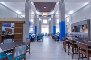 Un moderno vestíbulo de hotel con un área de estar central, una cocina y una recepción.