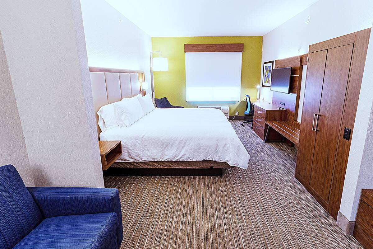 A hotel room with a bed, a desk, a chair, a television, and a wardrobe.