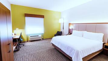 Una camera d'albergo con un letto, una scrivania, una sedia, una lampada e una finestra.