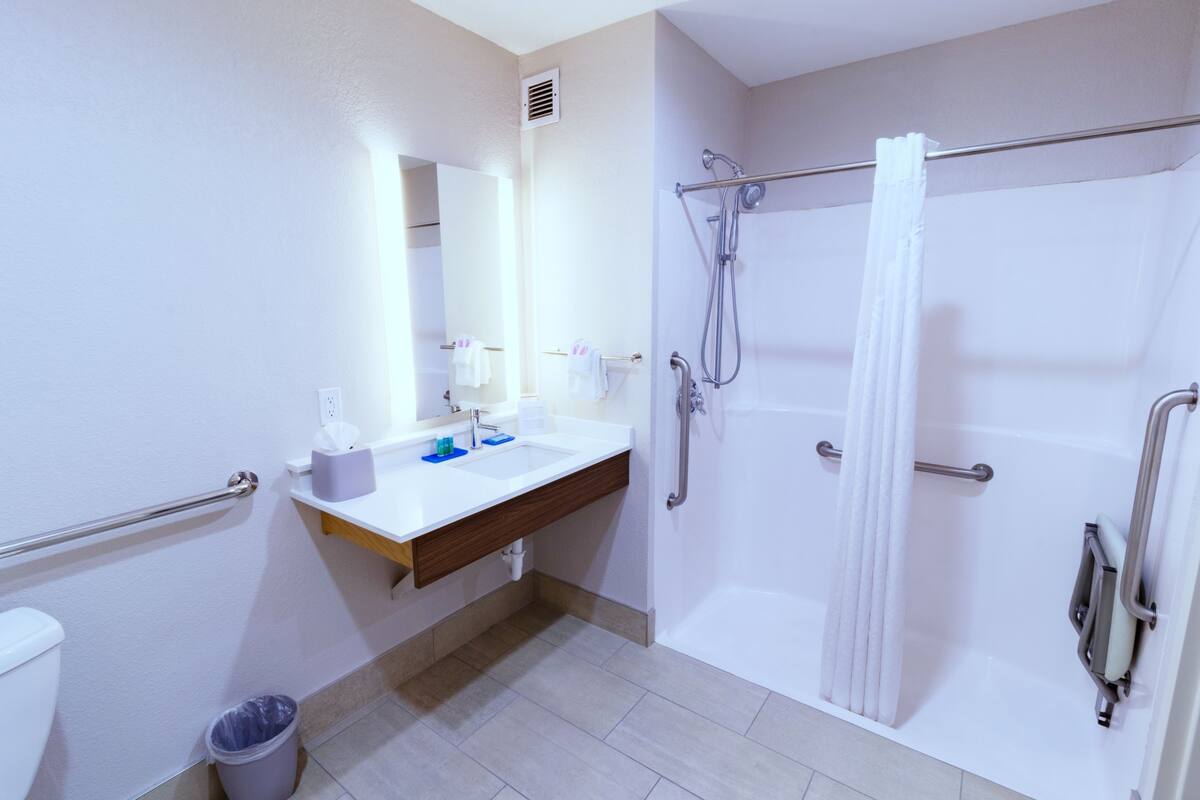 A modern bathroom with a white sink, mirror, and shower.