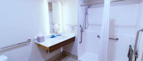 Une salle de bain avec un lavabo blanc, un miroir et un espace douche.